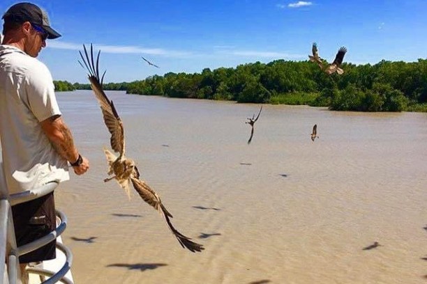 a man with a flock of kites flying over a body of water